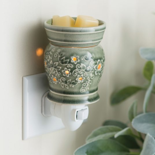 Decorative wall-mounted wax warmer with floral patterns on a neutral background